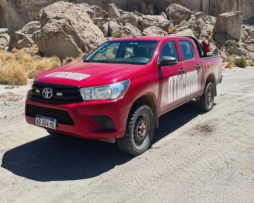 Hilux roja de Atacama con baliza, entre rocas de la Puna